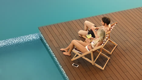 Cheerful-couple-drinking-cocktails-on-poolside-near-luxury-house.