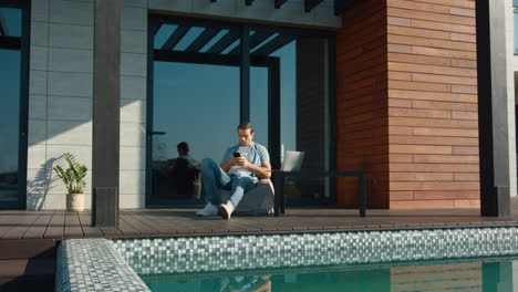 Casual-man-resting-with-mobile-phone.-Handsome-man-using-mobile-at-luxury-house