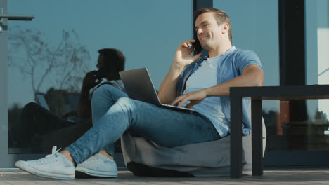 Handsome-business-trader-talking-phone.-Freelancer-working-laptop-computer