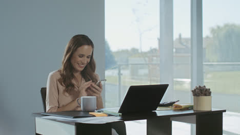 Business-woman-scrolling-mobile-at-work-place.-Smiling-lady-having-break.