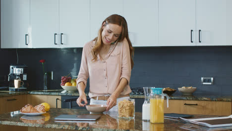 Happy-woman-preparing-healthy-breakfast.-Relaxed-person-speaking-on-mobile-phone