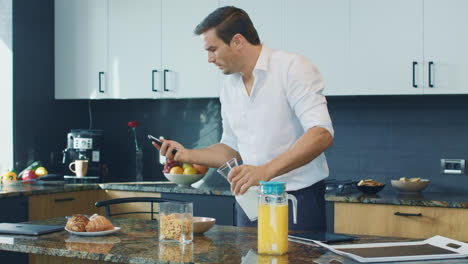 Business-man-preparing-breakfast-in-kitchen.-Professional-checking-mobile-phone.