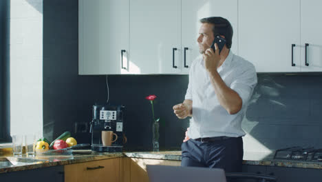 Business-man-making-coffee-at-luxury-kitchen.-Man-talking-cellphone-at-kitchen.