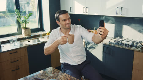 Business-man-making-selfie-photo-in-kitchen.-Topdown-portrait-of-smiling-man