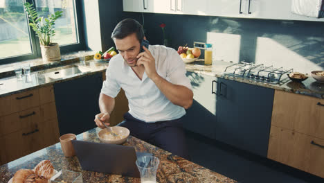 Happy-man-talking-phone-in-kitchen.-Relaxed-male-person-speaking-on-mobile.