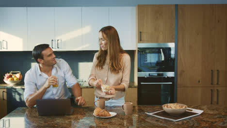 Happy-family-having-breakfast-at-kitchen.-Smiling-couple-talking-at-home.