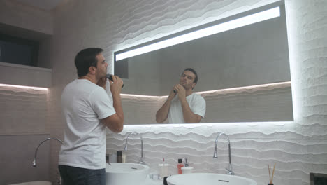 Handsome-man-shaving-beard-in-luxury-bath.-Concentrated-man-shaving-in-bathroom