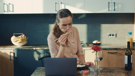 Beautiful-woman-eating-sushi-at-luxury-house.-Upset-woman-watching-laptop.