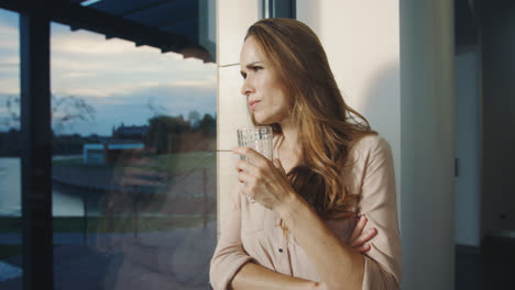Concentrated-woman-staying-near-panoramic-window.-Pretty-woman-waiting-for-man.