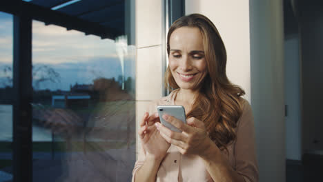 Happy-woman-looking-mobile-phone-near.-Smiling-woman-scrolling-smartphone.