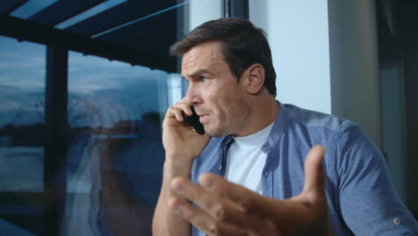Business-man-talking-mobile-near-window.-Nervous-man-explaining-his-position.