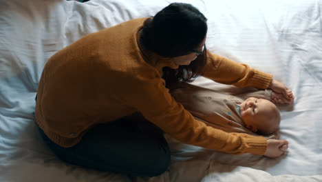 Loving-mother-playing-with-baby-in-bed.-Newborn-child-smiling-mother