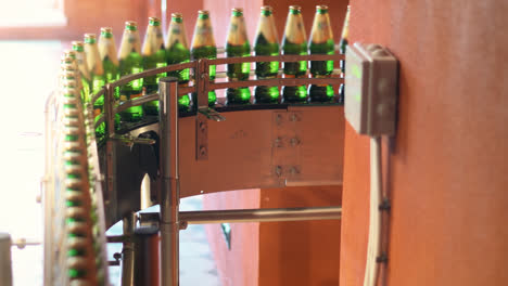 Green-bottles-on-conveyor-belt.-Beer-bottling-machine-working-in-brewery-factory