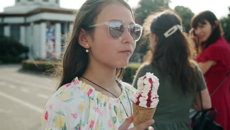 Pretty-girl-eating-ice-cream-cone.-Relaxed-teen-girl-walking-in-amusement-park