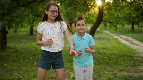 Smiling-brother-and-sister-dancing-outdoors.-Cute-kids-in-summer-park