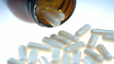 Herbal-pills-on-white-table.-Pharmatheutical-production.-Herb-capsule-in-tube