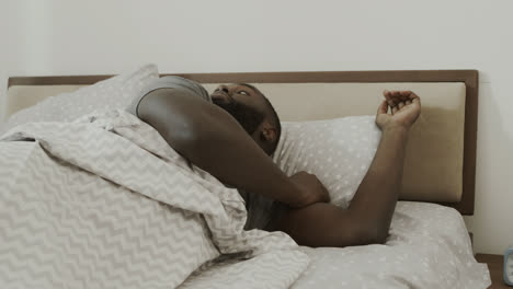 Black-man-waking-up-in-morning-suddenly.-Happy-adult-sitting-in-bed.