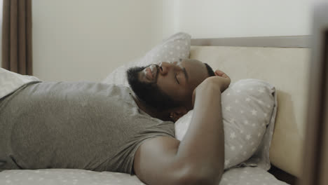 Black-man-sleeping-bed-in-morning.-Young-male-person-stretching-in-bed-slowly.