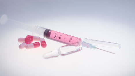 Syringe-with-pink-liquid.-Pharmaceutical-pills-and-medical-glass-ampule