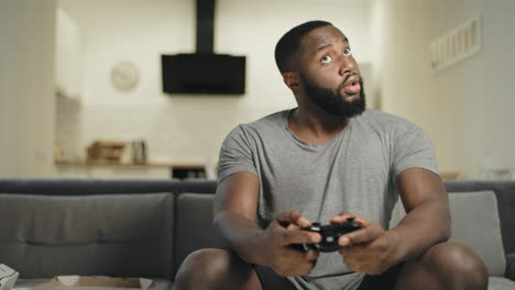 Playful-black-guy-playing-video-game-at-kitchen.-Upset-man-throwing-out-joystick