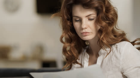 Young-woman-working-at-home.-Closeup-female-person-sitting-on-sofa-with-laptop.