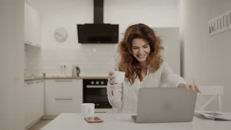 Happy-young-woman-making-coffee-at-kitchen.-Smiling-lady-getting-message