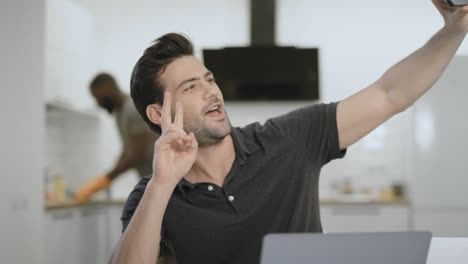 Handsome-man-taking-selfie-at-open-kitchen.-Young-guy-making-v-gesture.