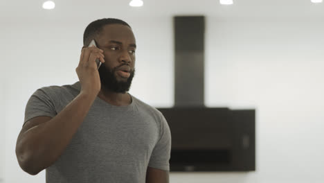 Angry-black-man-talking-phone-at-home.-Young-guy-listening-cellphone.