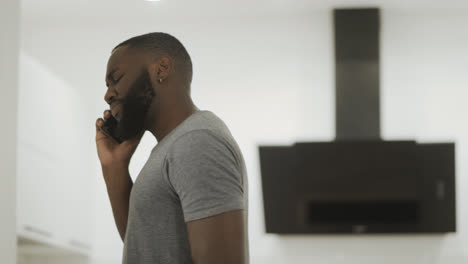 Arguing-black-man-talking-phone-at-home.-Angry-guy-speaking-cellphone.