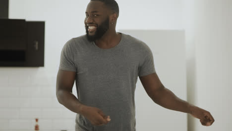 Happy-black-man-dancing-at-open-kitchen.-Young-guy-making-dance-at-home.