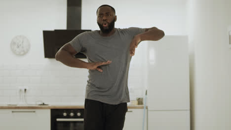 Happy-black-man-dancing-robot-at-open-kitchen.-Young-guy-moving-slowly-at-home.