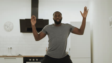 Serious-black-man-dancing-hip-hop-at-kitchen.-Young-dancer-warming-up-at-home.
