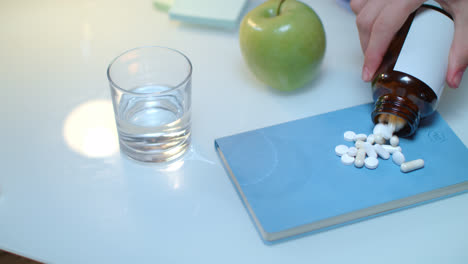 Hand-pour-tablet-and-capsules-from-bottle-on-table.-Healthy-medicine-concept