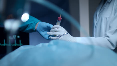 Surgeon-team-hands.-Surgeon-operating.-Gloved-hands-giving-blood-syringe