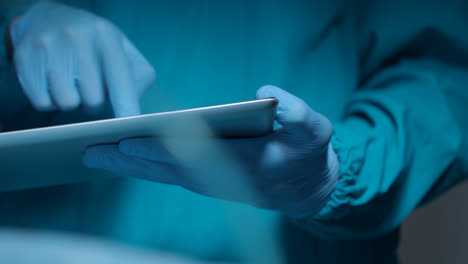 Gloved-hand-holding-tablet.-Diagnostic-technology.-Surgeon-hands-hold-tablet