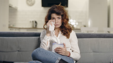 Crying-woman-watching-tv-at-living-room.-Portrait-of-sad-woman-wiping-face