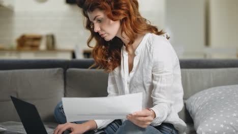 Concentrated-woman-working-home-in-day-time.-Pretty-girl-checking-paper.