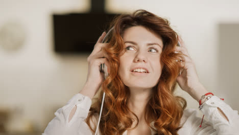 Young-woman-putting-headphones-at-modern-kitchen.-Closeup-girl-enjoying-music