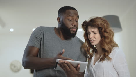 Young-couple-discussing-at-home-kitchen-together.-Black-man-showing-pictures
