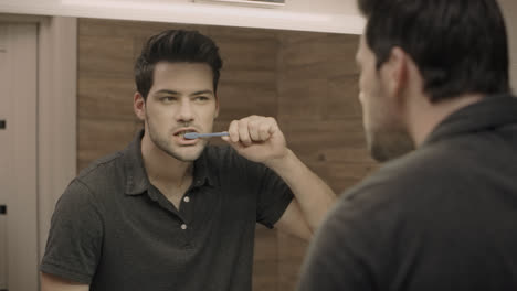 Concentrated-man-cleaning-teeth-in-bathroom.-Closeup-male-person-brushing-teeth