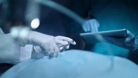 Surgeon-using-tablet.-Medical-tablet-in-surgery-hand.-Surgeon-operating-team