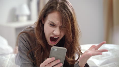 Shocked-woman-watching-video-news-online-on-mobile-phone-at-morning
