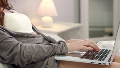 Woman-hands-typing-laptop-keyboard-in-bed.-Female-hands-typing-keyboard