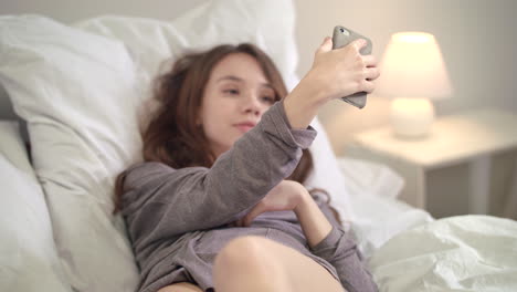 Sensual-woman-posing-for-mobile-selfie-in-bed.-Instagram-blogging