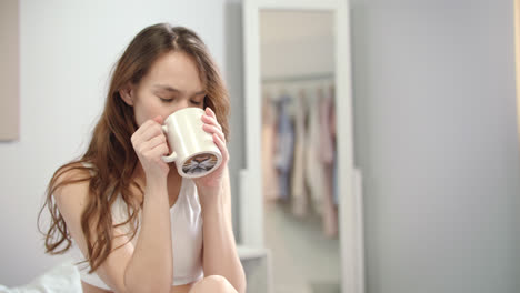 Young-woman-enjoy-morning-coffee-in-bed.-Portrait-of-happy-woman