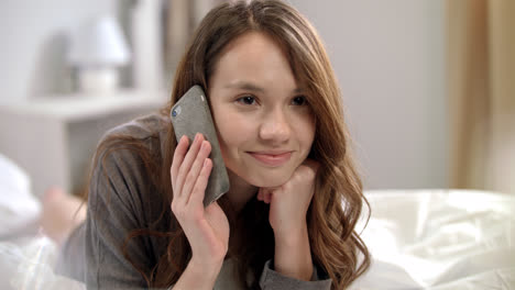 Young-woman-talking-on-mobile-phone-in-bed.-Smiling-woman-talking-on-phone