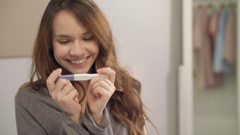 Happy-woman-taking-photo-of-pregnancy-test-on-mobile-phone