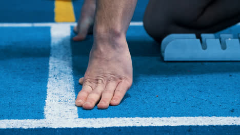 Fingers-of-sportsman-on-running-track-low-start-position.-Hands-of-athlete