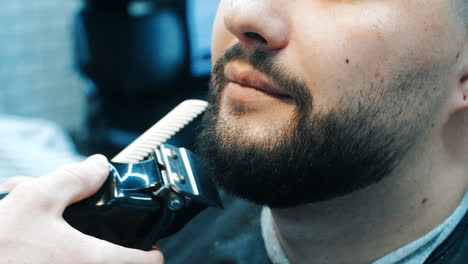 Skillful-hairdresser-cutting-male-hair-on-beard.-Grooming-beard-in-barbershop