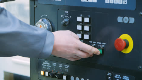 Engineer-starting-up-unit-by-pressing-buttons-on-control-panel